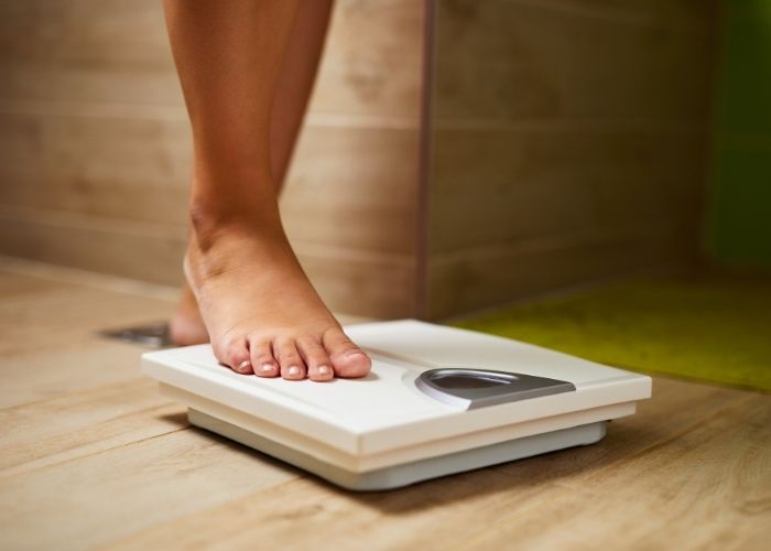 Femme sur une balance — lien entre le poids et l'estime de soi